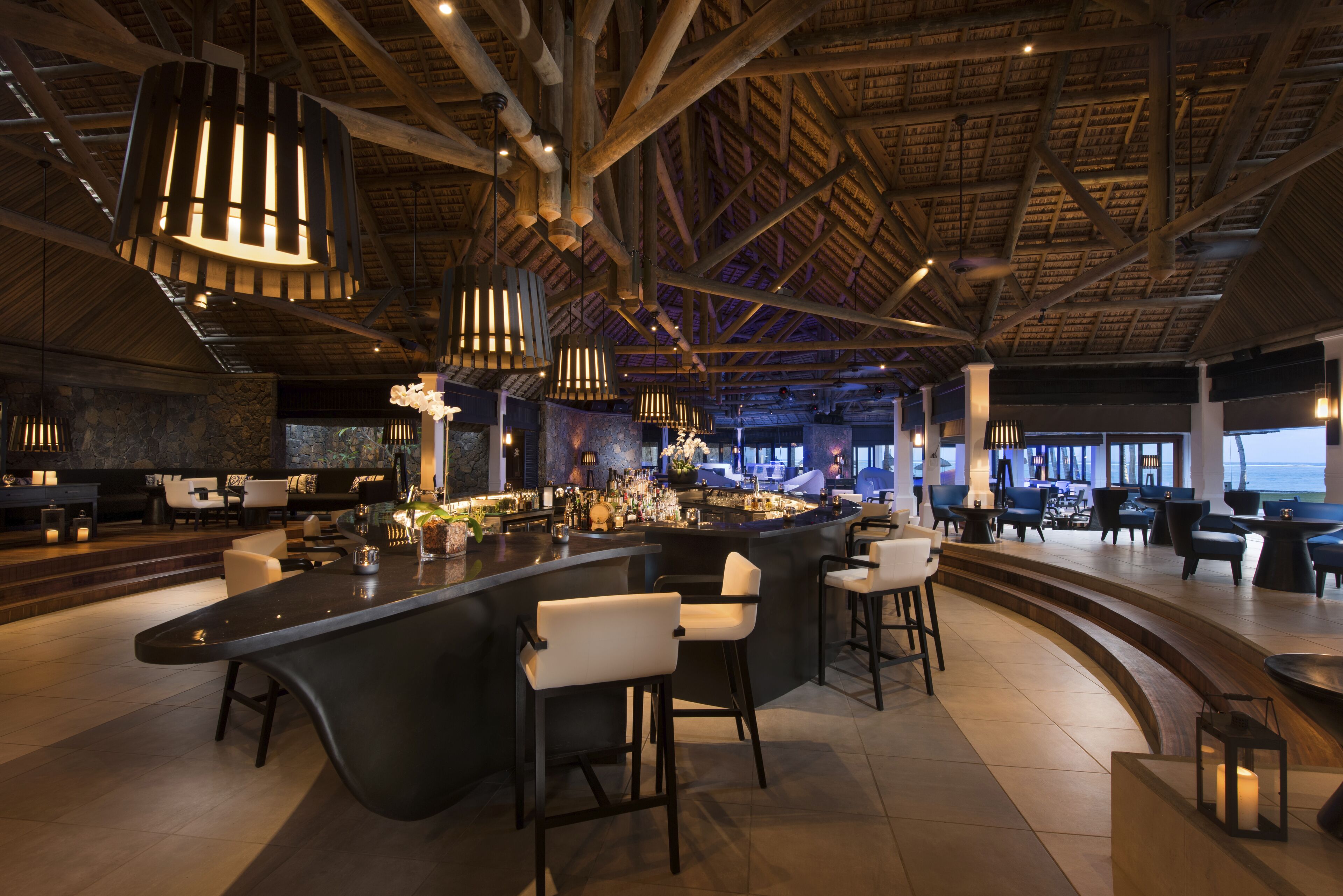 A modern bar area with high ceilings, exposed beams, and contemporary lighting fixtures.