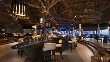 Eine moderne Bar mit hohen Decken, freiliegenden Balken und zeitgenössischen Leuchten.