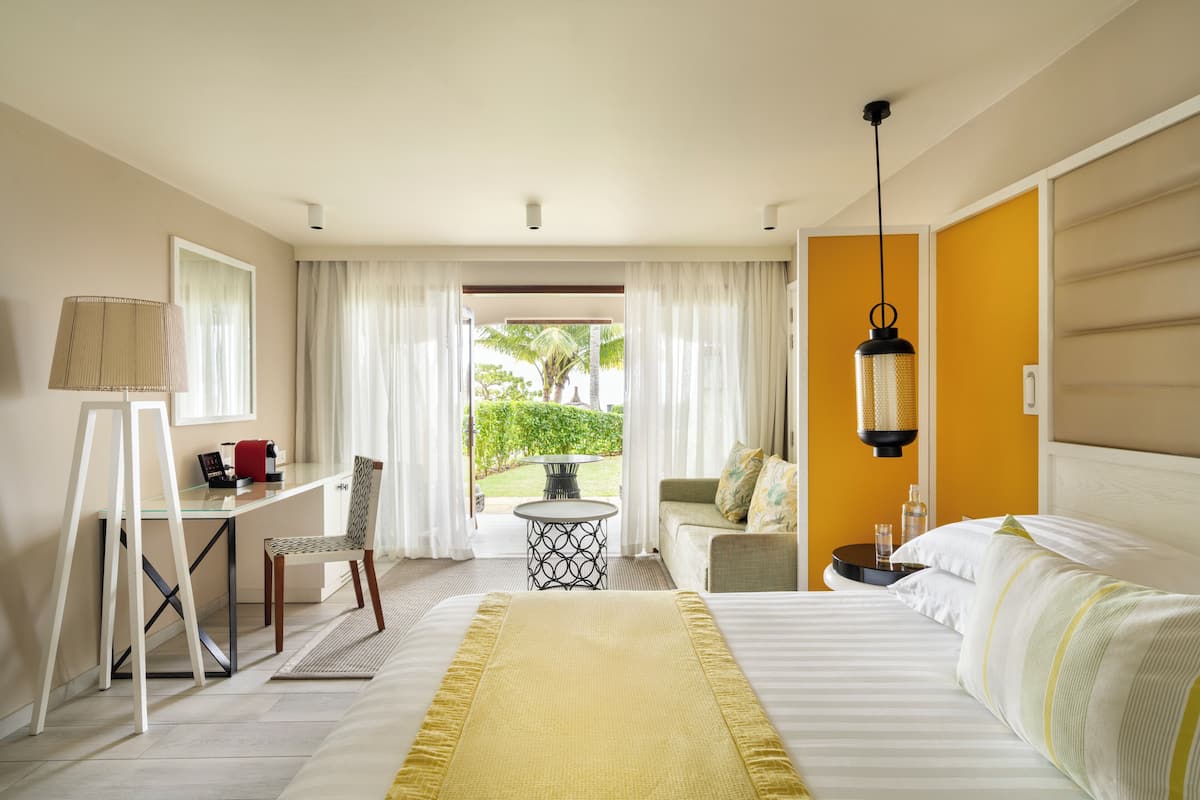 Habitación de hotel con cama, escritorio, silla, una mesita y vistas al exterior.
