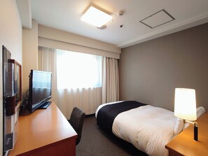 A hotel room with a bed, a desk with a television, a lamp, and a window with curtains. - APA Hotel Yamaguchi Hofu (Hofu)