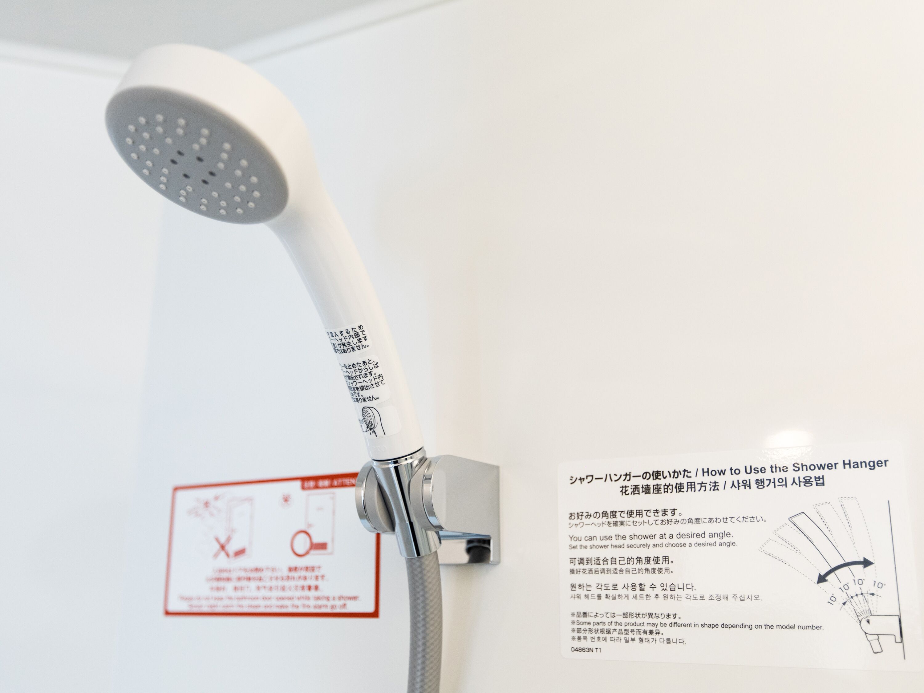 Eine Dusche mit flexibler Brause, ein Sicherheitsschild und ein Gebrauchshinweis-Plakat.
