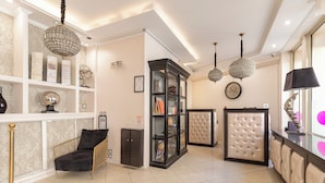 A modern hotel lobby with a black leather sofa, a glass display cabinet, and a tufted leather armchair. - Hotel Riviera (Paris)