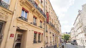 A hotel with a classic facade, a prominent red sign, and a bicycle parked outside. - Hotel Riviera (Paris)