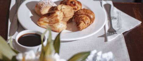 A plate of pastries and a cup of coffee on a table with a napkin and a spoon.