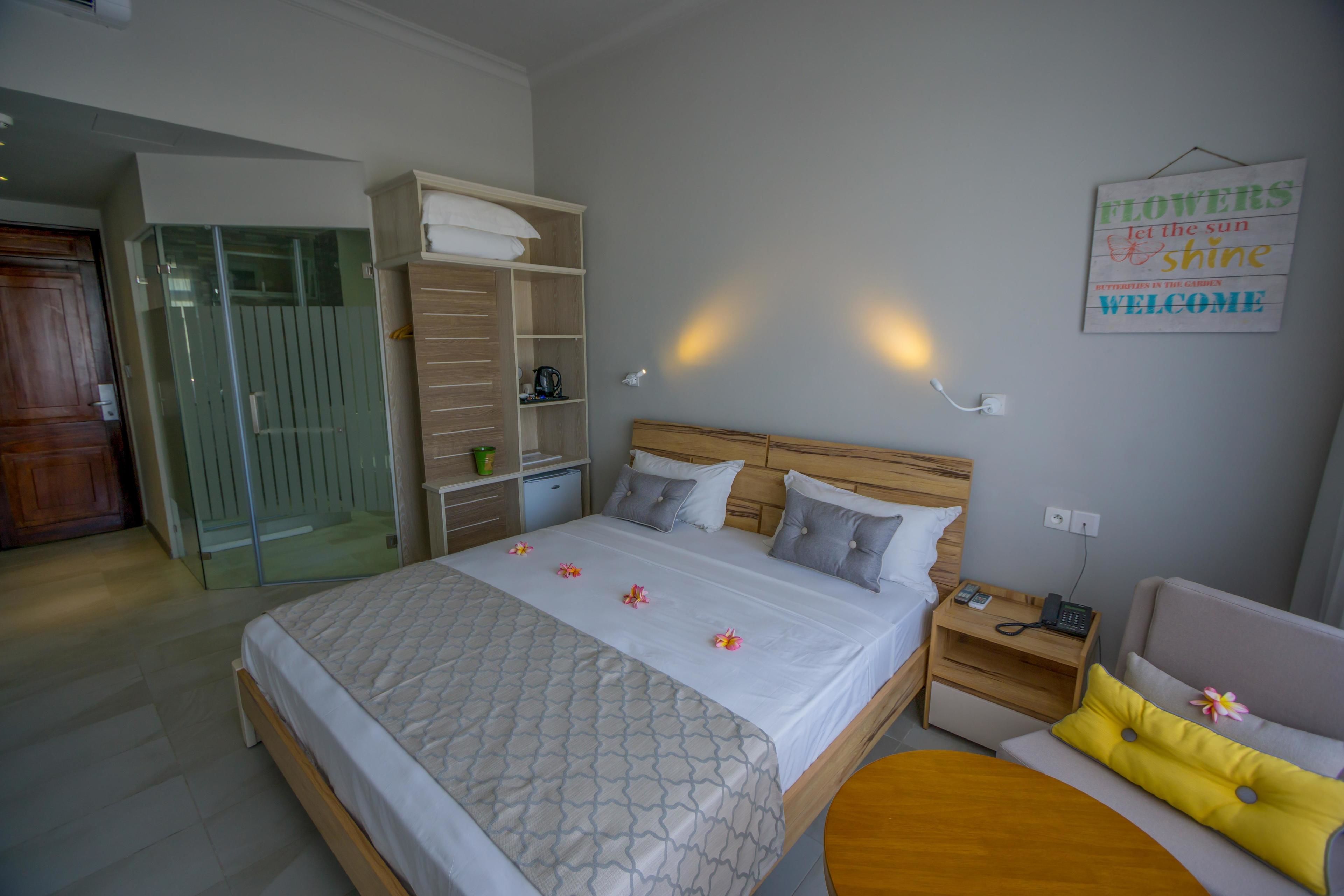 A hotel room with a large bed, a wooden headboard, a bedside table with a phone, and a small sofa.