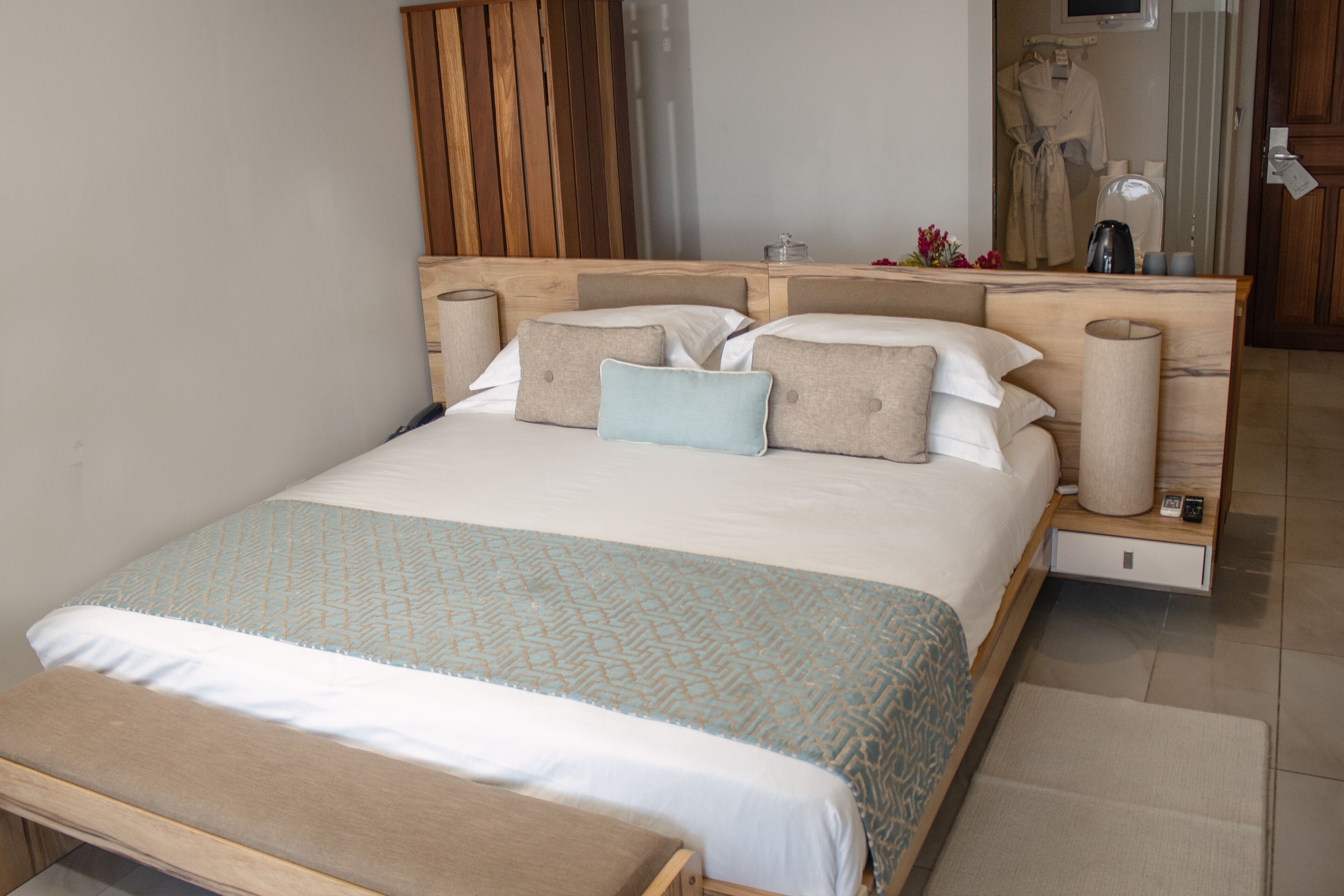 A neatly arranged bedroom with a large bed, bedside tables, and a wooden headboard.