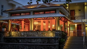 Una entrada de piedra con el letrero "Le Peninsula Bay Beach Resort & Spa".