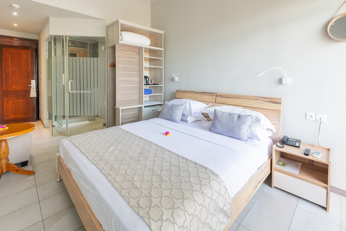 A neatly arranged bedroom with a bed, bedside tables, a wardrobe, and a shower area.