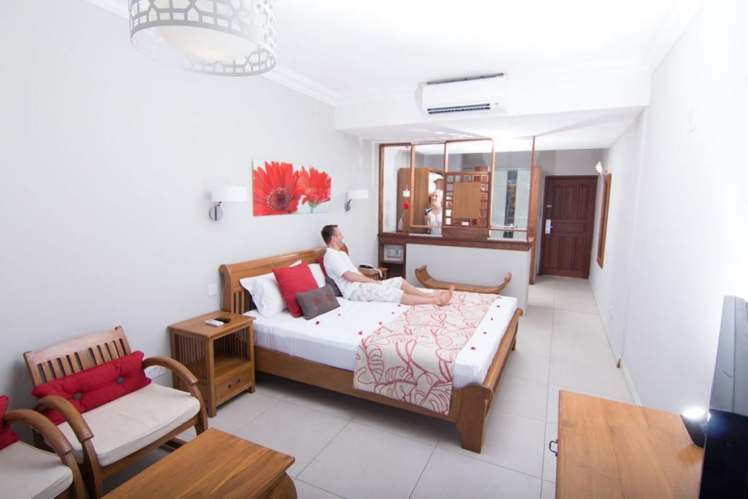 Una habitación con una cama, muebles de madera, un espejo y un ventilador de techo.