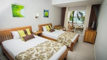 A hotel room with two beds, a wooden headboard, a nightstand, a small wooden cabinet, and a view of the outdoors.
