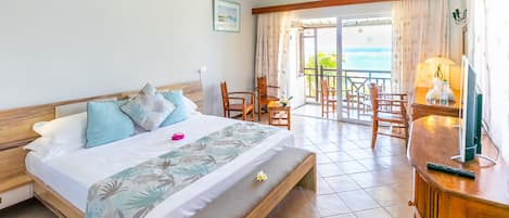 Een hotelkamer met een bed, een bureau en een balkon met stoelen.
