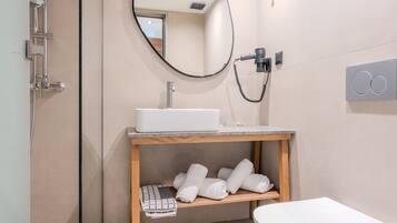 A modern bathroom with a white sink, a mirror, and a towel rack.