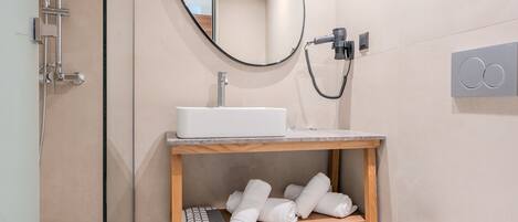 A modern bathroom with a white sink, a mirror, and a towel rack.