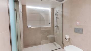 Une salle de bain moderne dotée d’une douche à parois de verre, de toilettes et d’un bidet.
