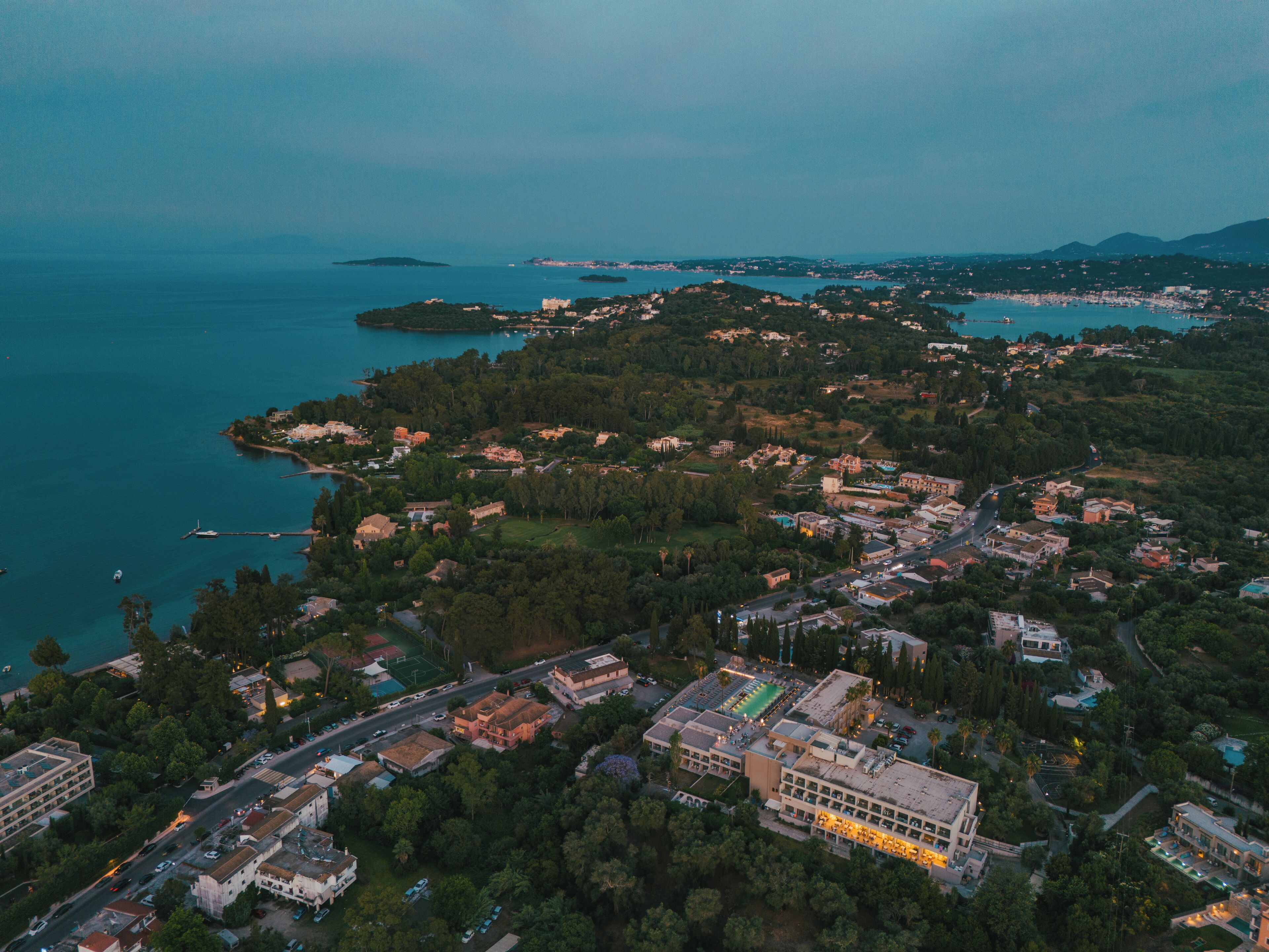 Vista aérea de uma cidade costeira com edifícios, estradas e um porto de iates.