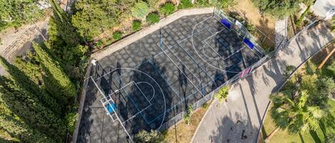 An aerial view of a basketball court surrounded by dense greenery.