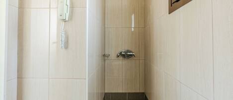 A small, narrow bathroom with a shower, a toilet, and a telephone.