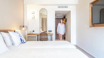 Una habitación de hotel moderna con una cama grande, un escritorio, una silla y un espejo.