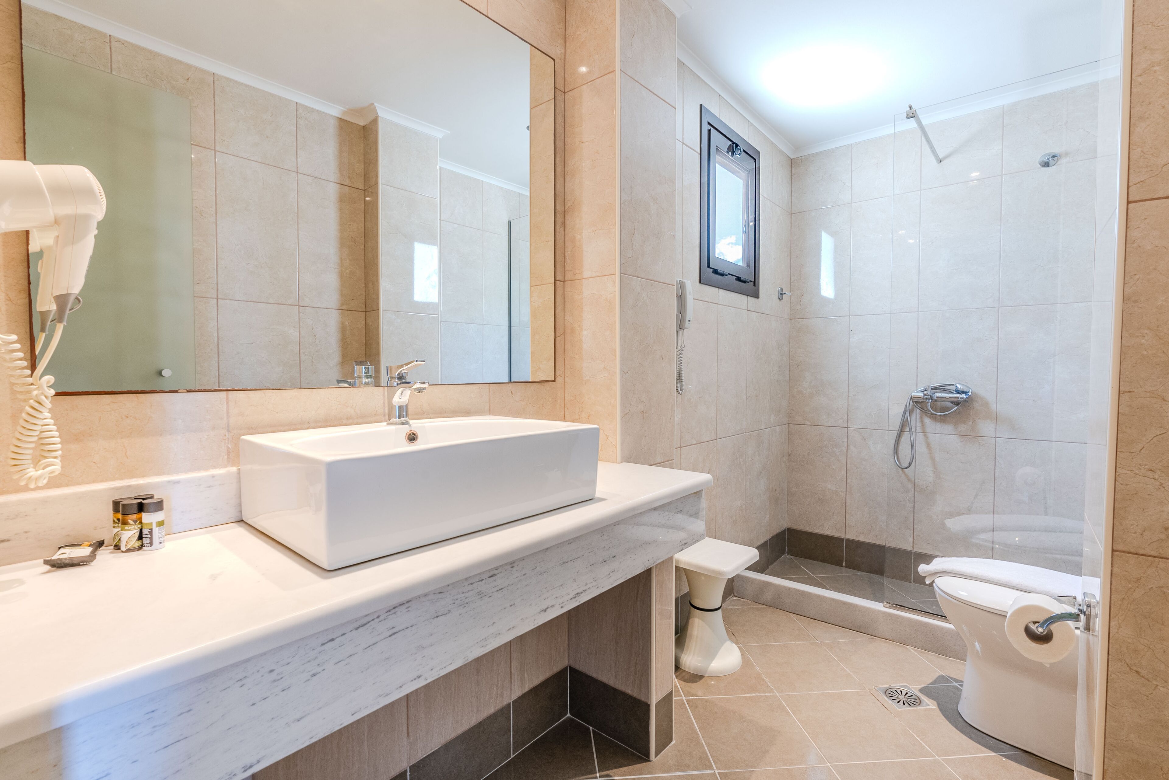 A modern bathroom with a large mirror, a sink, a toilet, and a shower area.