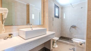 A modern bathroom with a large mirror, a sink, a toilet, and a shower area.