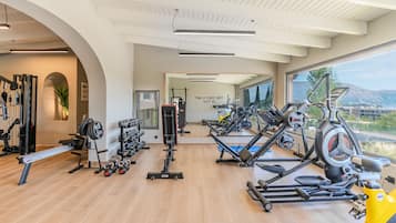 Een moderne sportschool met diverse fitnessapparaten, een rek voor gewichten en een groot raam met uitzicht op de omgeving.