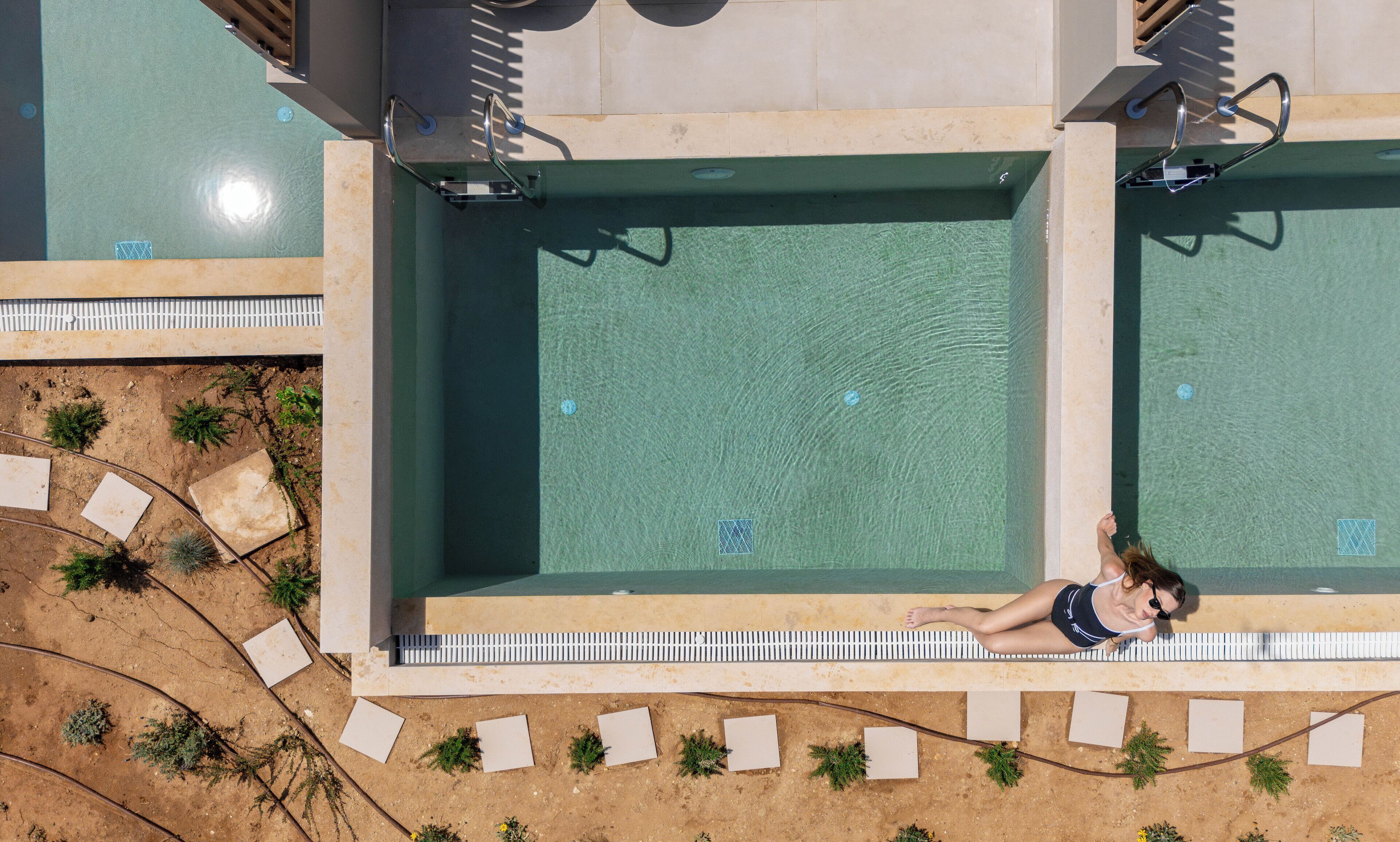 An aerial view of a swimming pool with a person relaxing on the edge.