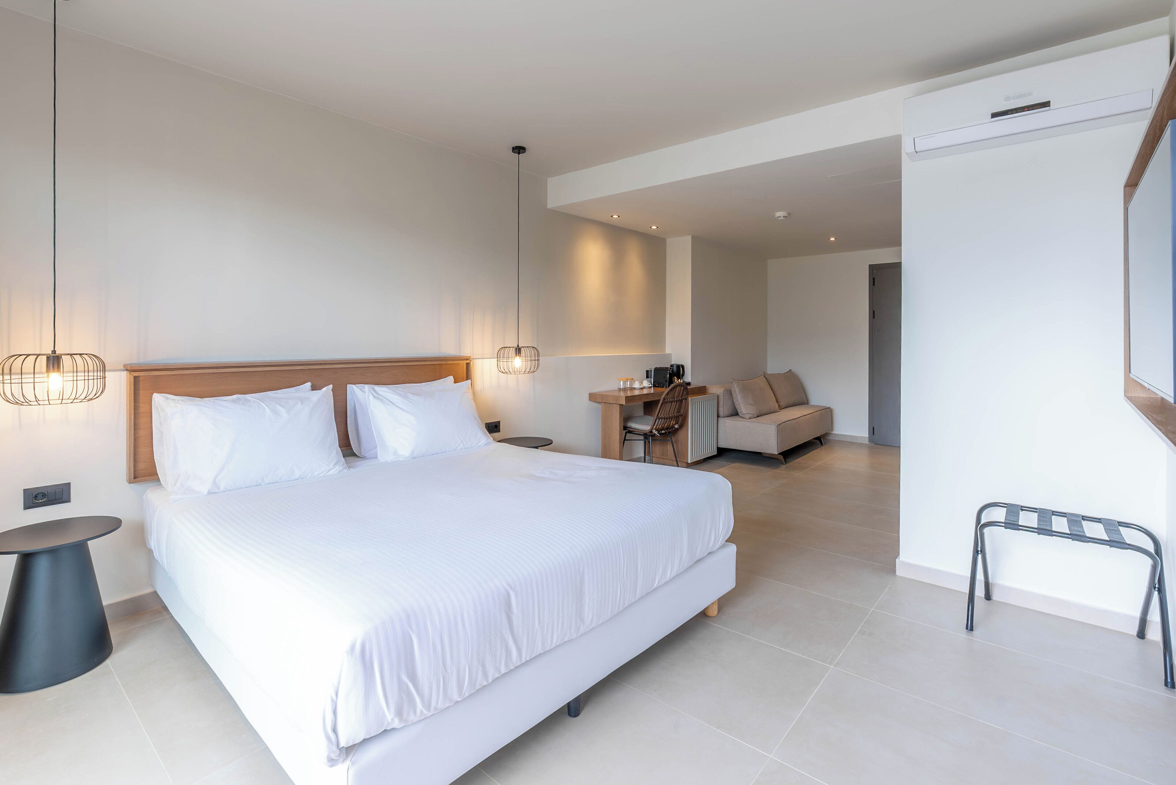 A modern hotel room with a large bed, bedside tables, a desk, and a chair.