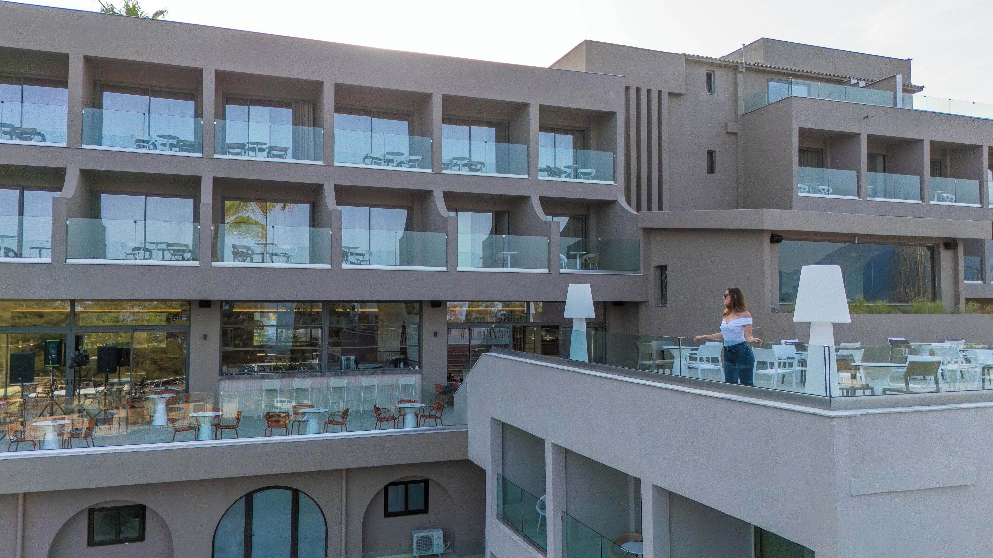 A multi-story hotel with outdoor seating areas on each floor, large windows, and a modern architectural design.