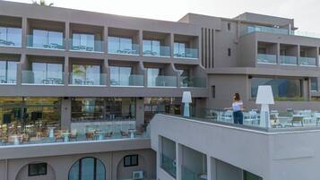 A multi-story hotel with outdoor seating areas on each floor, large windows, and a modern architectural design.