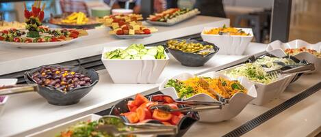 A buffet with various food options including salads, fruits, and vegetables.