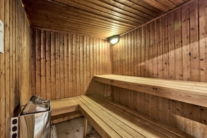 A sauna with wooden walls and benches, a bench heater, and a light fixture. - Hotel Santana (St. Paul's Bay)