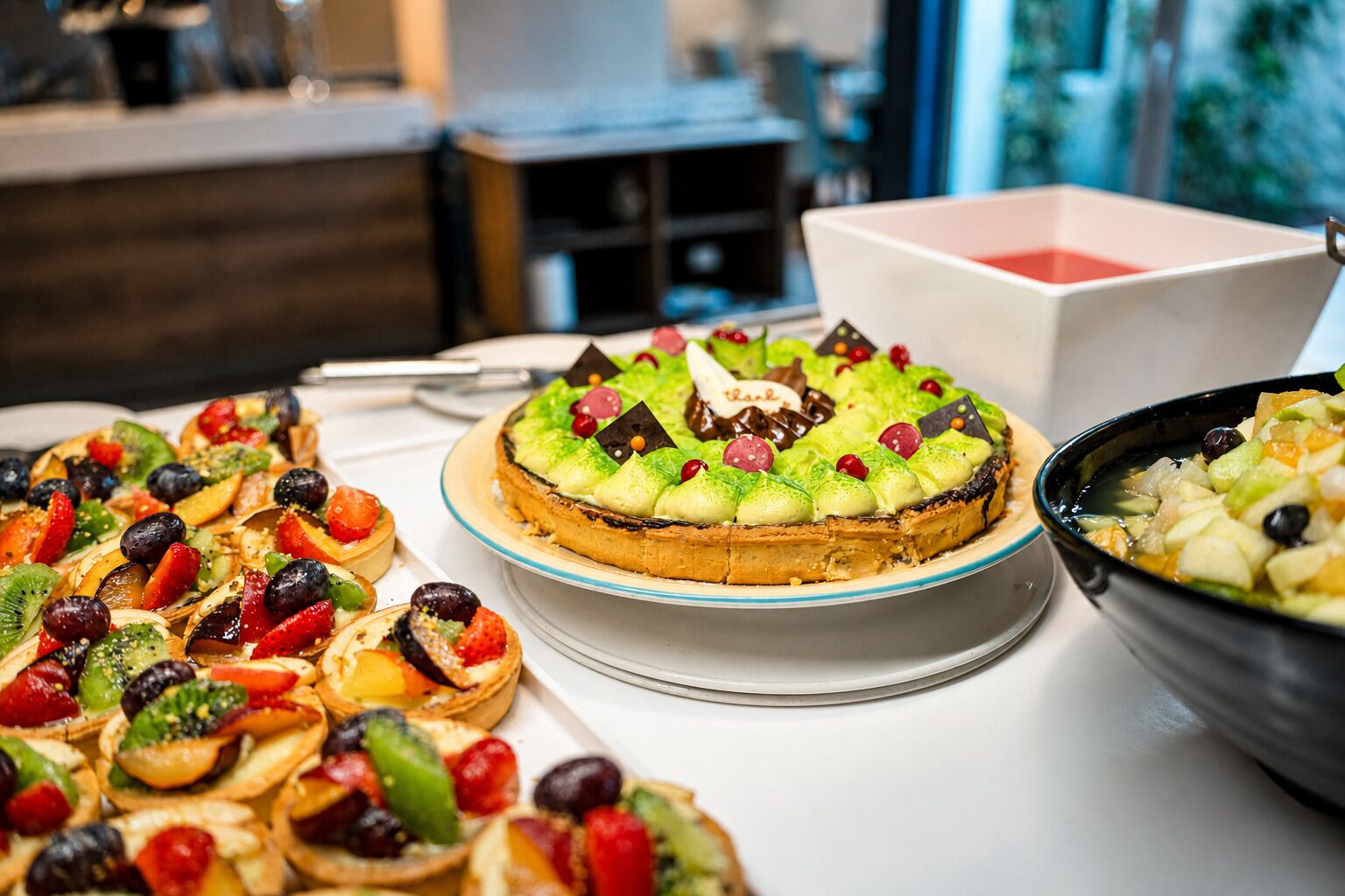 Diverse desserts op een tafel, waaronder een fruittaart en fruitsalade.