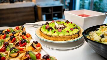Variedad de postres sobre una mesa, incluyendo una tarta de frutas y una ensalada de frutas.
