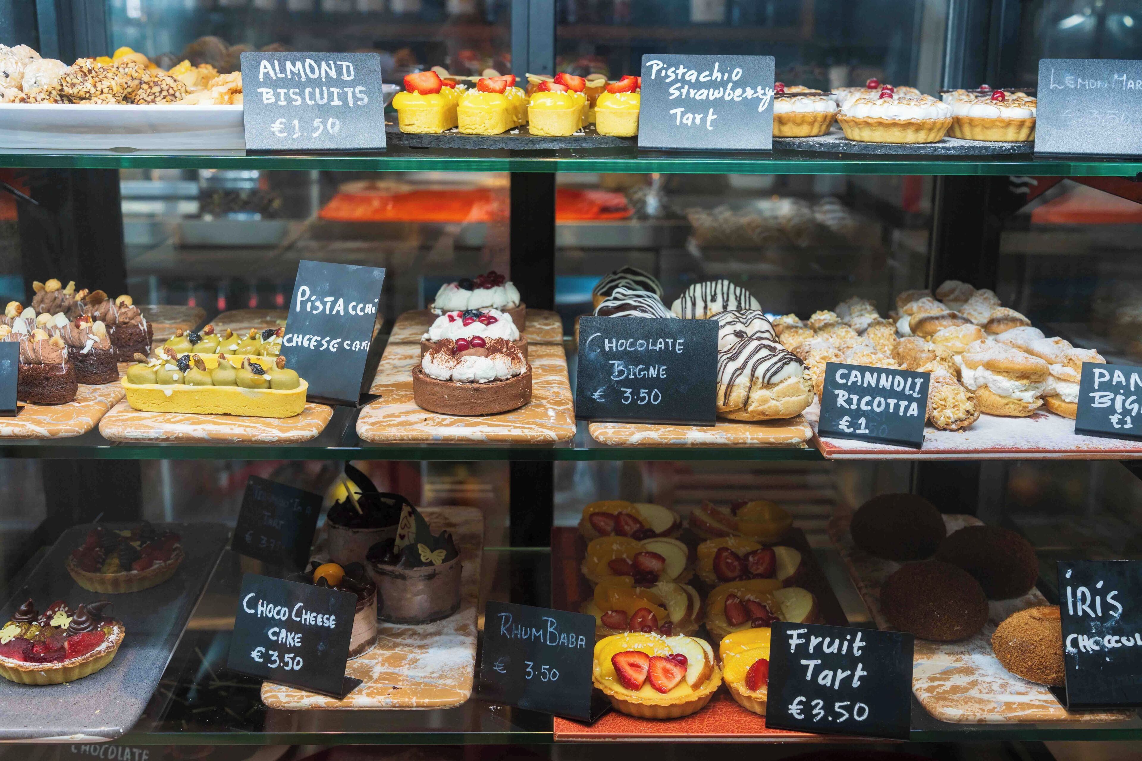 Diverse desserts uitgestald in een glazen vitrine met prijzen.