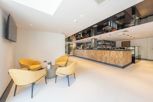 Un interior moderno con una zona de bar, asientos y un televisor de pantalla plana.