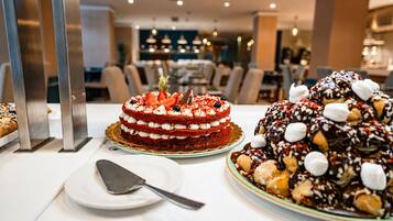Una presentación de postres con un pastel de terciopelo rojo en capas, un pastel con cobertura de chocolate y un plato con una espátula para pasteles.