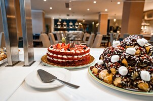 Una presentación de postres con un pastel de terciopelo rojo en capas, un pastel con cobertura de chocolate y un plato con una espátula para pasteles.