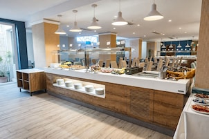 Un moderno montaje de buffet con diversas opciones de comida, una barra con platos y un área de comedor con sillas.
