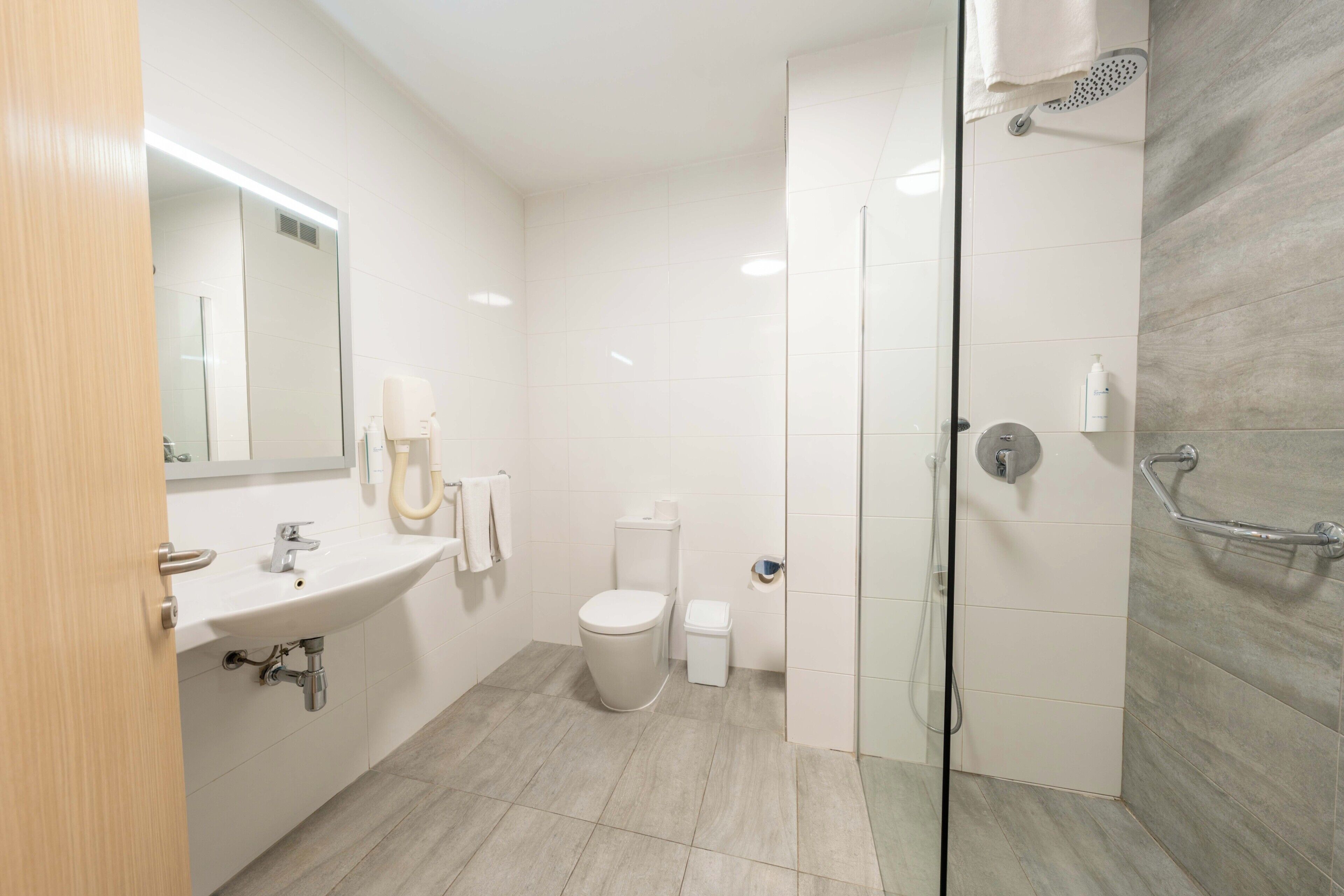 Un baño moderno con lavamanos, inodoro y ducha.
