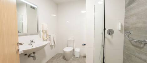 Un baño moderno con lavamanos, inodoro y ducha.