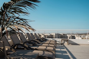 Una terraza en la azotea con sillones de descanso y una palmera.