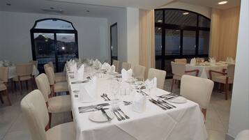 A dining area with tables set for a meal, featuring white tablecloths and chairs.