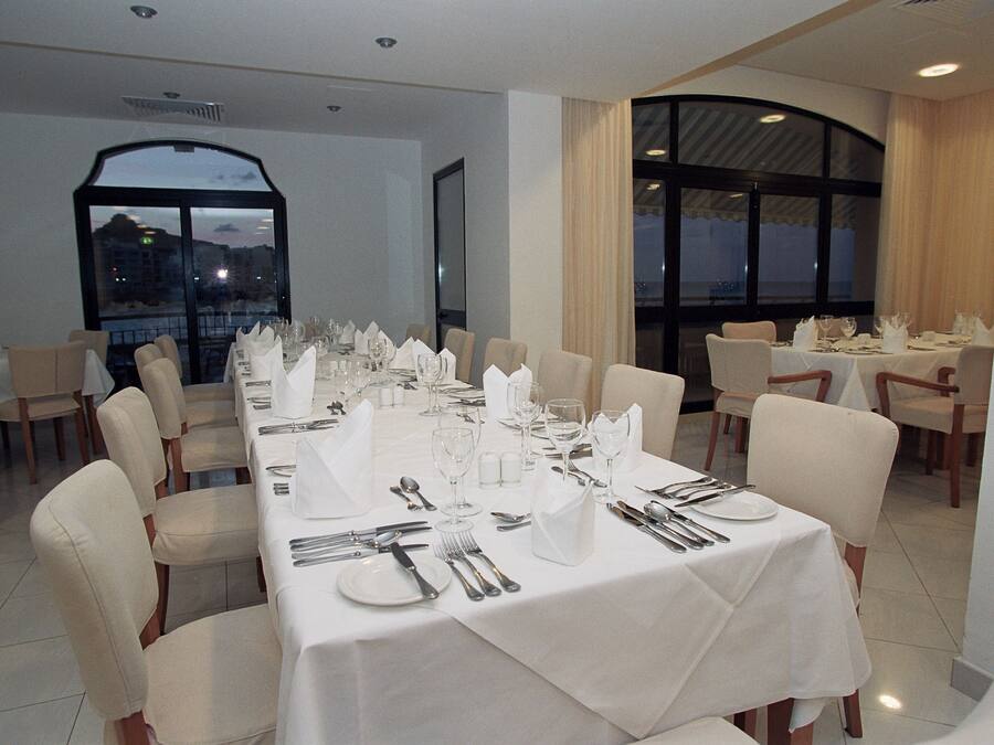 A dining area with tables set for a meal, featuring white tablecloths and chairs.