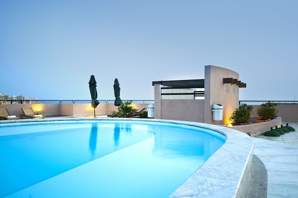 Una piscina al aire libre de temporada, sombrillas