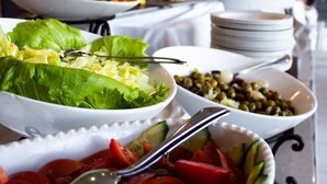 A buffet table with various dishes including salads, vegetables, and fruits.
