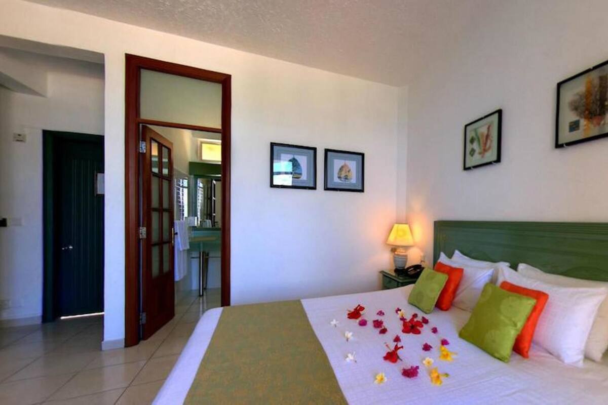 Une chambre d’hôtel avec un lit, une table de chevet, une lampe et deux tableaux encadrés au mur.