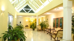 A spacious indoor area with a high ceiling, large windows, and several potted plants. - Silver Beach (Trou d'Eau Douce)