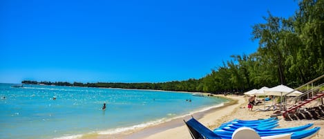 Am Strand, weißer Sandstrand, Liegestühle, Sonnenschirme