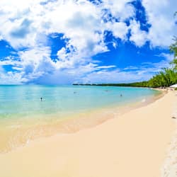 Na praia, areia branca, espreguiçadeiras, guarda-sóis