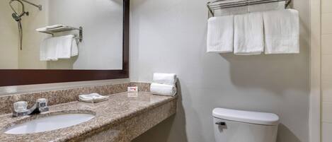 Un bagno con due lavandini, un water, un portasciugamani e uno specchio.